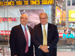 Two men standing in Times Square in front of the NASDAQ MarketSite